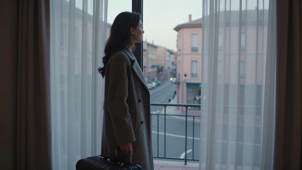 A woman stands by a hotel window at dawn, looking out with quiet dignity.